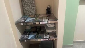 Pieni, käytännöllinen keittiönurkkaus, jossa on sisäänrakennettu liesi, pieni roskakori ja hylly, jossa on siististi taiteltuja pyyhkeitä.