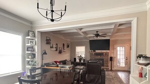 Un salon spacieux comprenant un coin repas, une cheminée et un téléviseur.