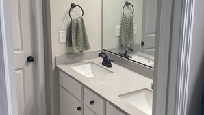 Une salle de bain avec un double lavabo, un grand miroir et un porte-serviettes.
