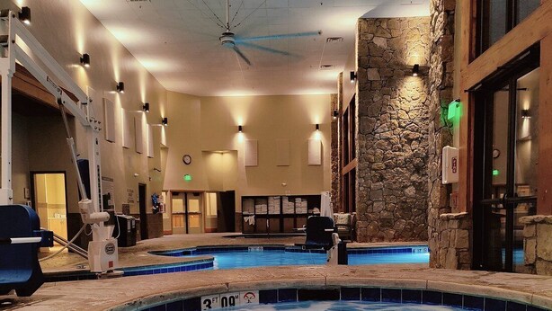 An indoor swimming pool with a stone wall and a ceiling fan. - Beautiful Family Friendly Luxury Resort - 2.20.26 to 2.27.26 - Tons of Amenities (Breckenridge)