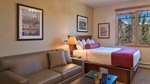 A hotel room with a bed, a sofa, a table with candles, and framed pictures on the walls. - Beautiful Family Friendly Luxury Resort - 2.20.26 to 2.27.26 - Tons of Amenities (Breckenridge)