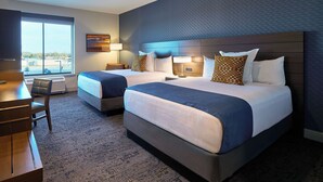 Une chambre d’hôtel avec deux lits, un bureau et une chaise.