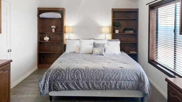 Camera da letto con un letto, comodini, uno scaffale con oggetti decorativi, una lampada a sospensione e una finestra con persiane.