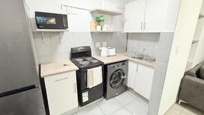 Una cucina compatta con frigorifero, microonde, piano cottura, forno e lavatrice.