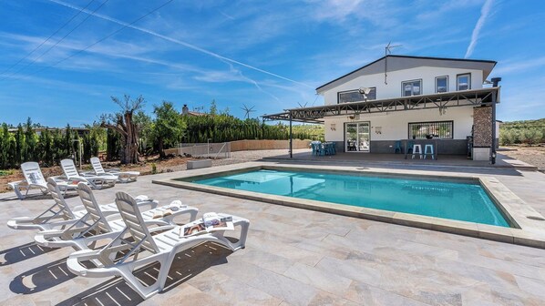 A modern house with a swimming pool, lounge chairs, and a patio area. - Casa Rural Las Flores Nigüelas by Ruralidays (Granada)