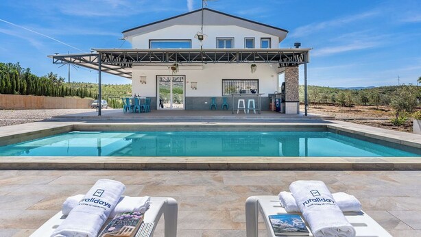A modern hotel with a pool, lounge chairs, and a covered outdoor area. - Casa Rural Las Flores Nigüelas by Ruralidays (Granada)
