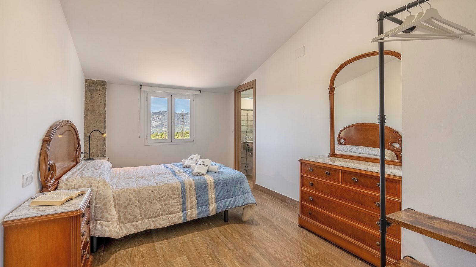 Ein Schlafzimmer mit Bett, Schminktisch und Spiegel.
