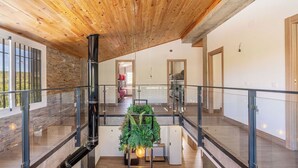A spacious interior with a high ceiling, a central staircase, and a view of a bedroom with a bed and a red chair. - Casa Rural Las Flores Nigüelas by Ruralidays (Granada)