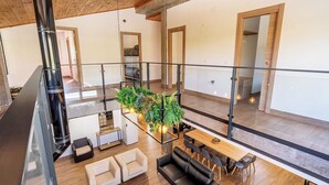 A spacious loft-style living area with a glass railing, a central plant arrangement, and a dining area with a long table and multiple chairs. - Casa Rural Las Flores Nigüelas by Ruralidays (Granada)