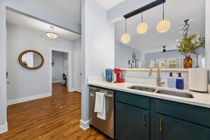 Una cocina moderna con lavavajillas de acero inoxidable, un lavamanos doble y piso de madera.