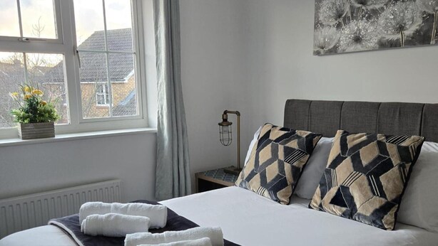 A neatly made bed with white and dark blue linens, two pillows with a geometric pattern, and two rolled towels on the bed. - Garden - Pets - Parking - Wifi - Sleeps 2 (Ashford)