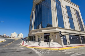A modern building with a curved facade, large windows, and a visible entrance with steps leading up to the door. - Fully Equipped Apartments With a Prime Location 600 m From Itapema Beach Lprs (Itapema)