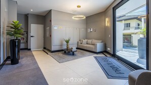 Un hall d’hôtel moderne avec un comptoir d’accueil, un canapé, une plante en pot et une grande fenêtre donnant sur l’extérieur.