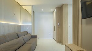 Un salon moderne avec un canapé, un téléviseur fixé au mur et une armoire en bois.
