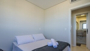 Une chambre d’hôtel avec un lit, une salle de bain visible à travers une porte ouverte et une fenêtre.