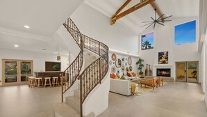 Ein großzügiger Wohnbereich mit Wendeltreppe, Kamin und Barbereich mit Hockern.