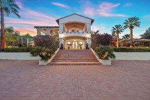 A large, two-story building with a central entrance, surrounded by palm trees and well-maintained landscaping. - Casablanca - 5 Acre, 8 Bedroom Compound (Palm Desert)