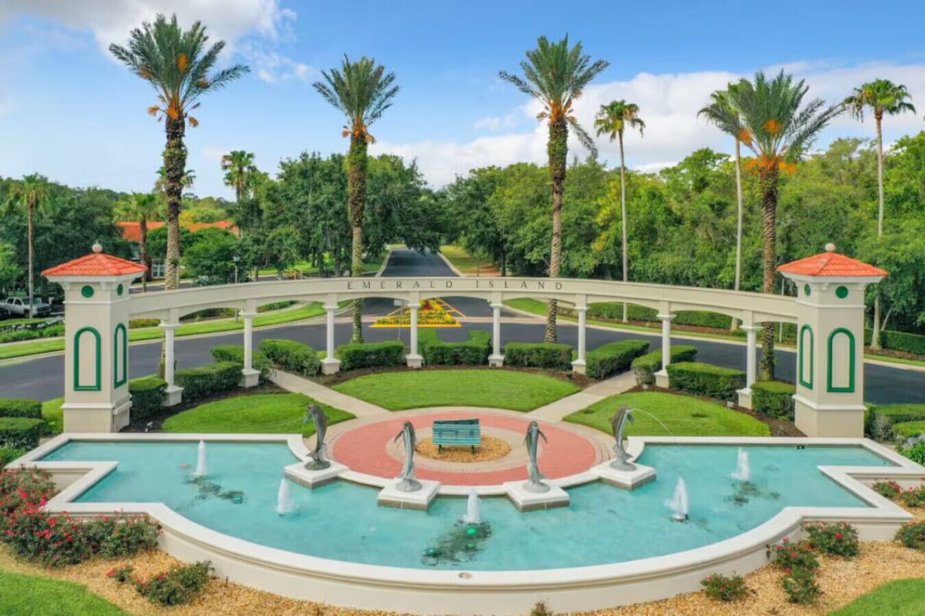 Ein angelegter Gartenbereich mit einem zentralen Brunnen, Palmen und einer Brücke mit der Aufschrift 'Emerald Island'.