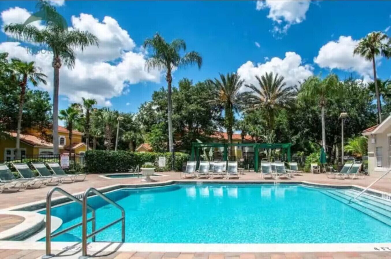 A swimming pool with lounge chairs and palm trees.