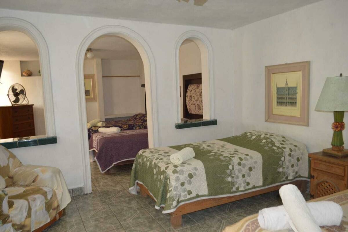 A room with a bed, a chair, a dresser, and a mirror. There are two archways leading to another room.
