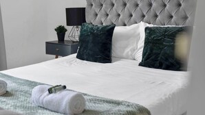 A neatly made bed with white linens, two dark green pillows, and a green blanket. - Stylish 4bed Home Free Parking 20 Min to Edinburgh (Livingston)