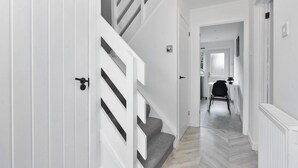 A modern hallway with a staircase leading to a dining area. - Stylish 4bed Home Free Parking 20 Min to Edinburgh (Livingston)
