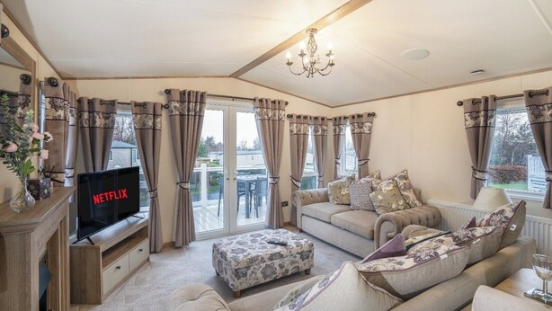 Ein gemütliches Wohnzimmer mit Kamin, Fernseher und einem Balkon mit Vorhängen.