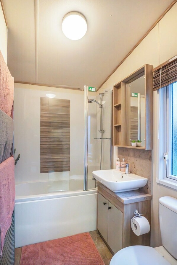 Une salle de bain moderne avec une douche à parois de verre, un lavabo blanc et des toilettes.