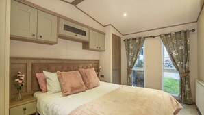 Ein Schlafzimmer mit Bett, Nachttisch, Kommode und einem Fenster mit Vorhängen.