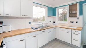 Een moderne keuken met witte kasten, een houten aanrechtblad en een raam dat voor natuurlijk licht zorgt.