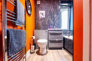 A compact bathroom with a toilet, sink, and mirror. - Airport Apartment - Aberdeen - Free Parking (Aberdeen)