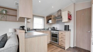 Cocina moderna con una isla central, horno empotrado, microondas y estufa. Se observa una puerta de madera y un extintor de incendios montado en la pared.