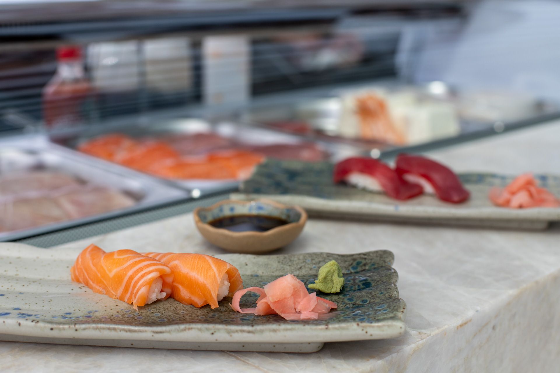 Un assortimento di sushi su piatti in ceramica, con una piccola ciotola di salsa di soia in primo piano.