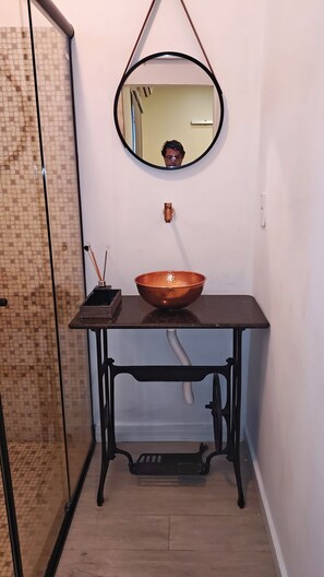 A bathroom with a glass shower enclosure, a copper basin on a black table, and a mirror on the wall. - 02 Suite Boulevard with kitchen (Centro Manaus)