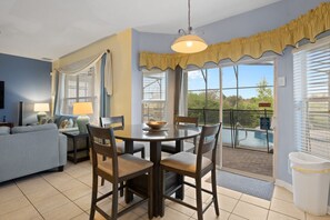 A dining area with a table and chairs, a sofa, and a lamp. - Windsor Hills Fun 6BR Villa, Pool/Spa, By Disney (Kissimmee)