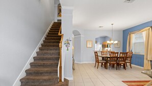 Eine Treppe mit Teppichstufen und Holzhandläufen, die in einen Essbereich mit Tisch und Stühlen führt.