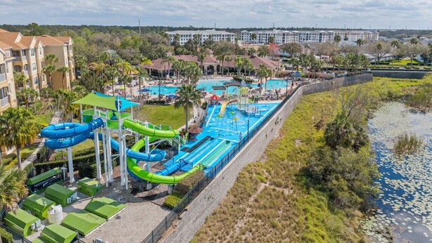 Ein Wasserpark mit mehreren Wasserrutschen und Pools, umgeben von Gebäuden und viel Grün.
