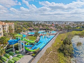 Ein Wasserpark mit mehreren Wasserrutschen und Pools, umgeben von Gebäuden und viel Grün.