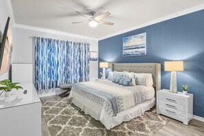 A bedroom with a bed, two bedside tables, a ceiling fan, a window with curtains, and a painting on the wall. - Luxury 10BR Windsor Island Home, Pool, Game Room (Davenport)