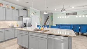 Eine moderne Küche mit Granit-Arbeitsplatten, Edelstahlgeräten und blau gepolsterten Stühlen an einem Esstisch.