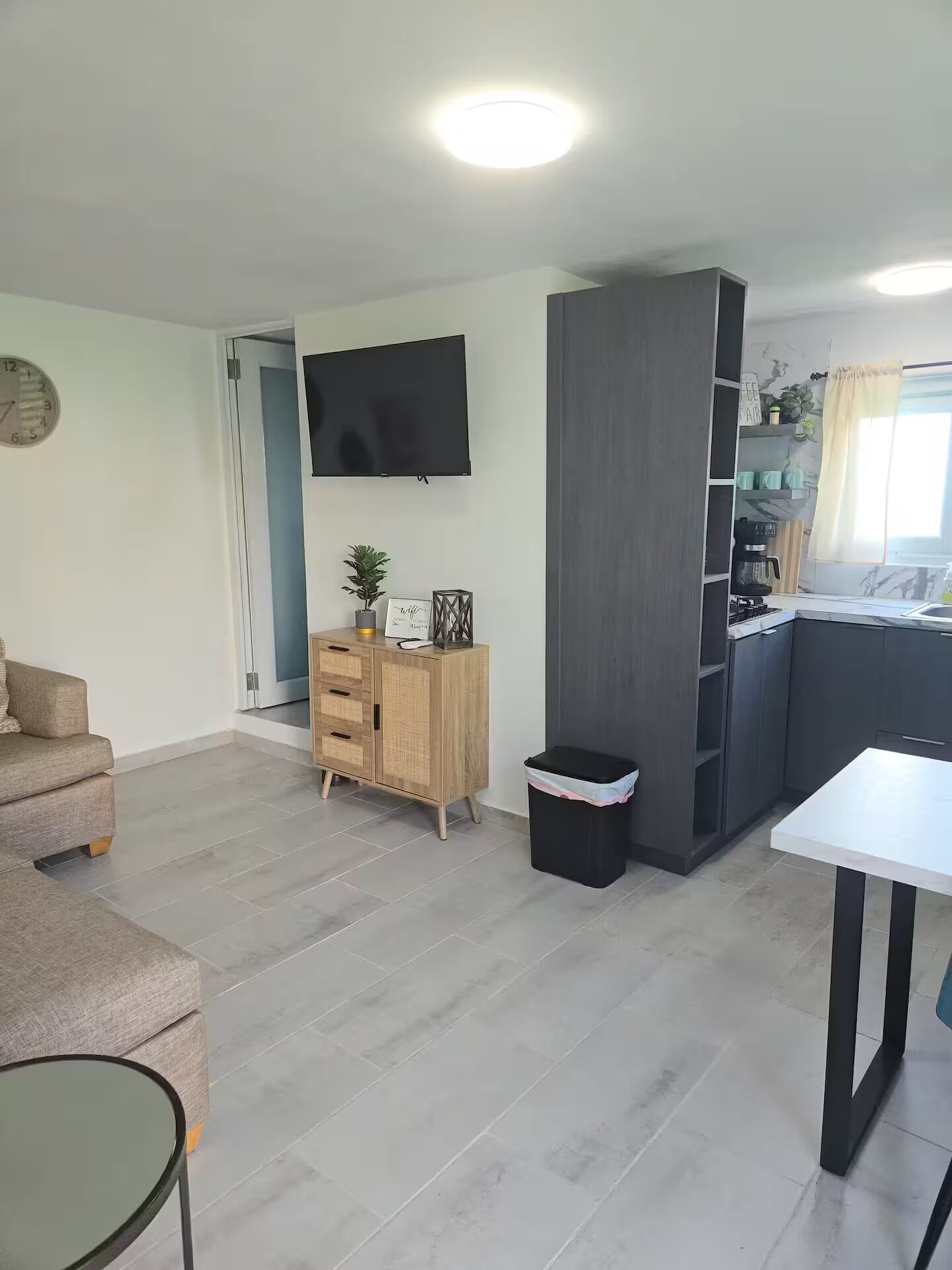 A modern living room with a sofa, a small table, a TV, and a wooden cabinet.
