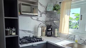 A kitchen with dark wood cabinets, a gas stove, a coffee maker, and a marble backsplash. - Piscina Vista II Ocean & Mountain Views with Solar (Ceiba)