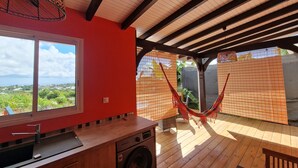 A kitchen with a large window, a washing machine, and a hammock in a covered outdoor area. - LE MALIATA "Villa Vue Mer piscine Privée" (Sea View Private Pool) (Saint-François)