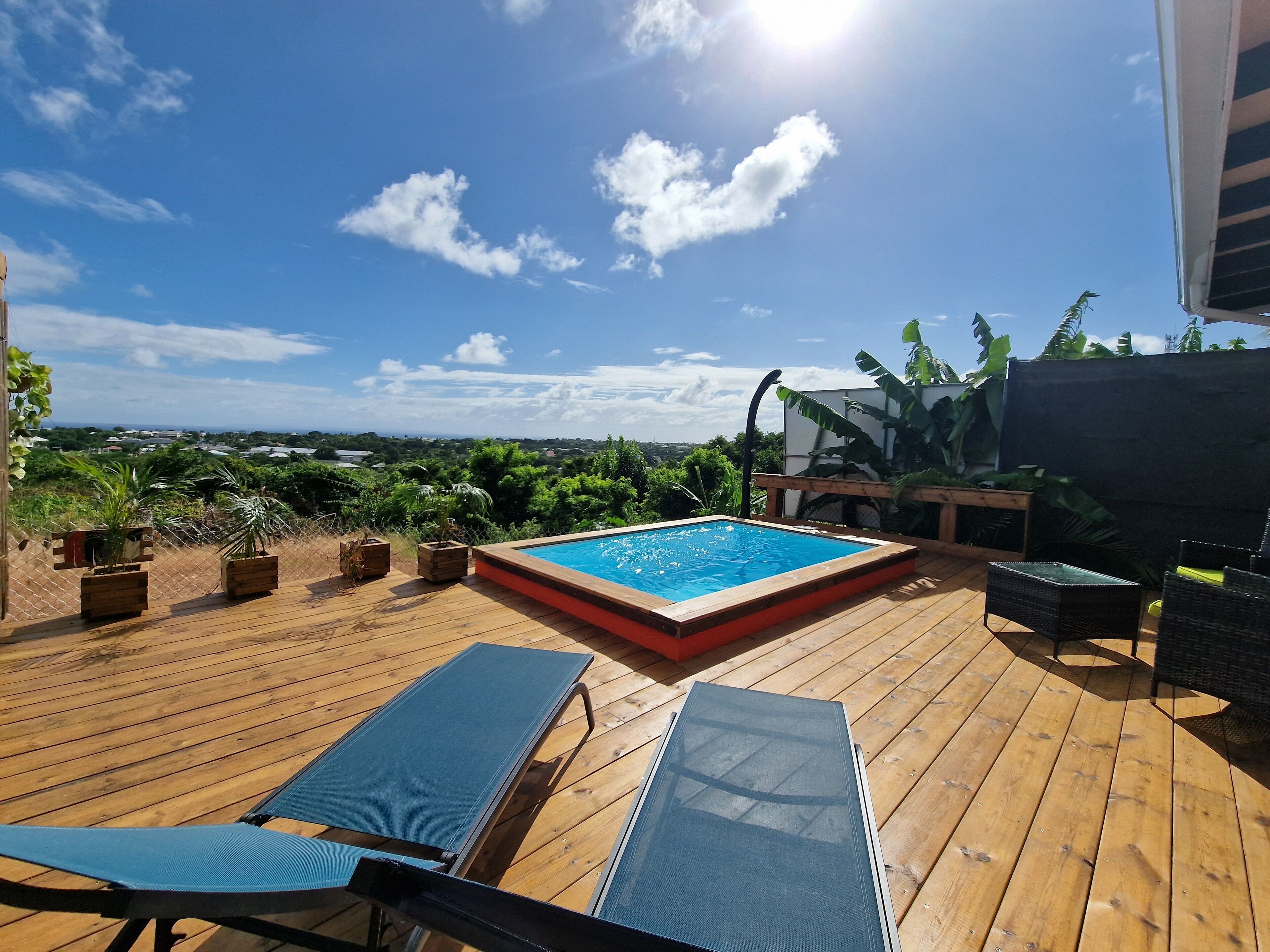 Une terrasse en bois avec une piscine, des chaises longues et des plantes en pot.