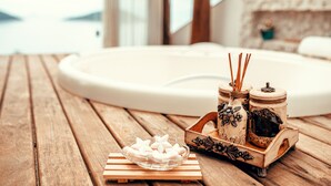 A wooden table with a glass bowl of white candles, two decorative jars, and a small wooden tray. - Luxury Oceanfront Villa with Infinity Pool, Sauna & Total Privacy (Arraial do Cabo)