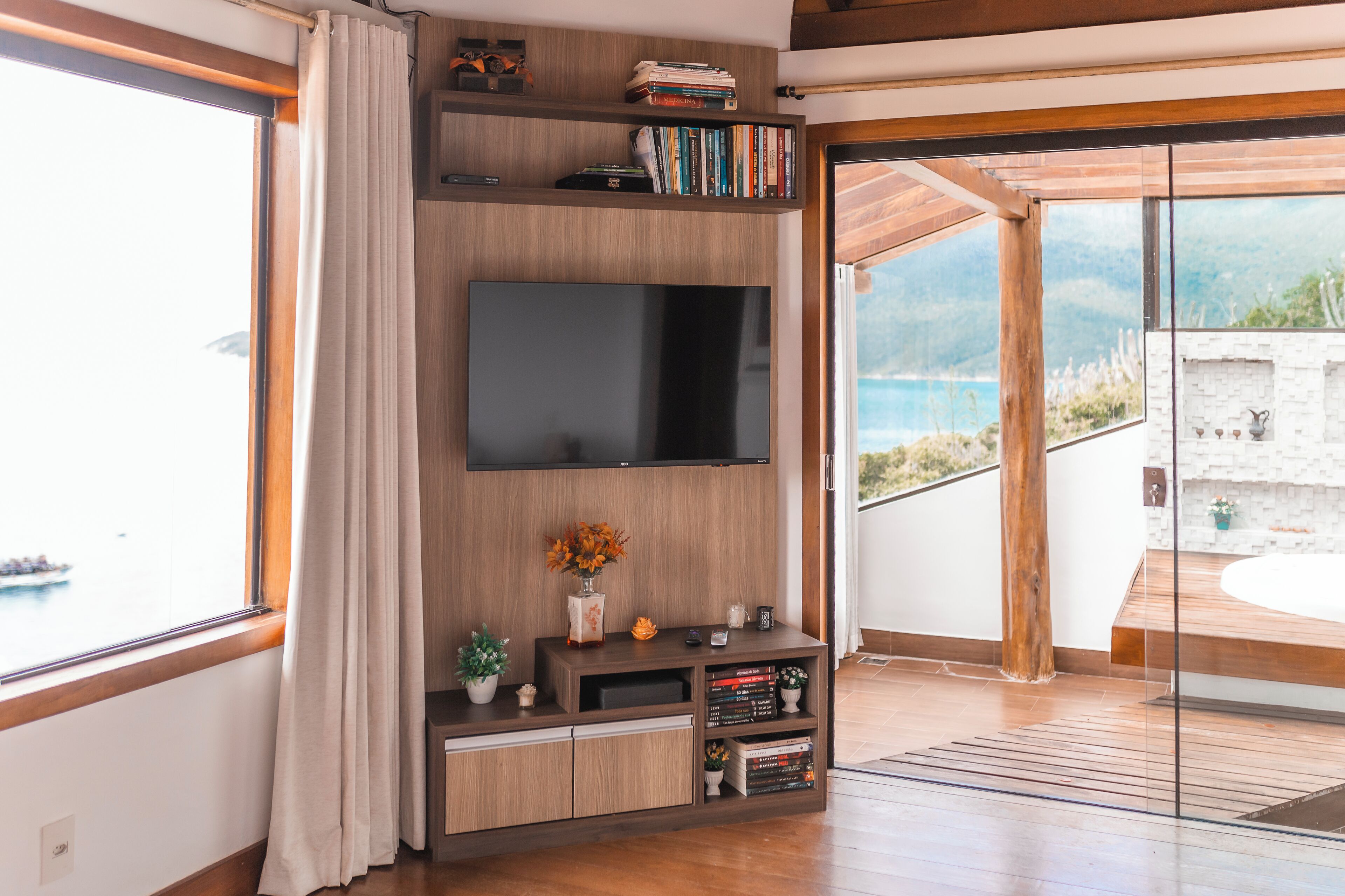 Una sala de estar moderna con un televisor de pantalla plana grande montado en una pared de madera, una estantería y una pequeña planta sobre una mesa consola.
