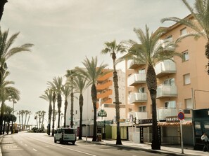 Eine Straße gesäumt von Palmen und ein Gebäude mit Balkonen.
