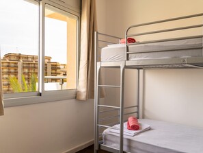 A bunk bed room with a window, a view of buildings, and a ladder. - Apartaments Corall 1C with seaview (Salou)