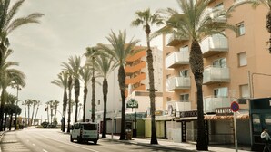 A street lined with palm trees and a building with balconies. - Apartaments Corall 2C with seaview (Salou)