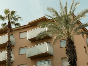 Ein mehrstöckiges Gebäude mit Balkonen, Palmen und blauem Himmel.